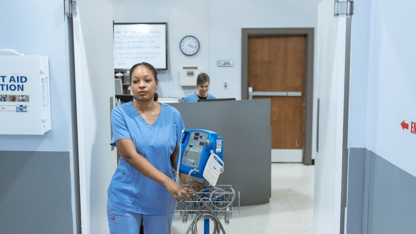 Infirmière en blouse bleue dans un couloir